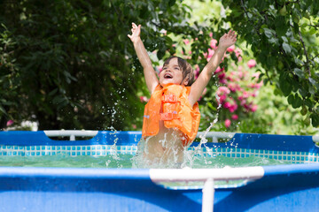 Happy child playing  in the pool in the garden on a hot summer day. Summer time concept background....