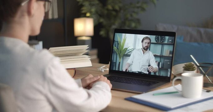 Confident woman talking to her bearded partner throught video conference on portable computer. Business people working from home during quarantine time.