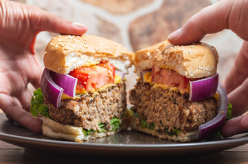 Two people's hands sharing a vegetarian burger