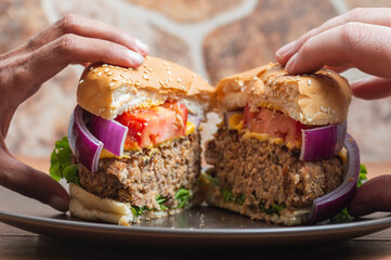 Two people's hands sharing a vegetarian burger