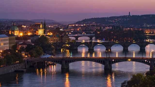 Prague, Czech Republic, dolly right timelapse sequence showing Prague cityscape with medieval bridges and boats on the Vltava river at dusk.