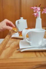 Woman having breakfast in bed, taking a piece of croissant