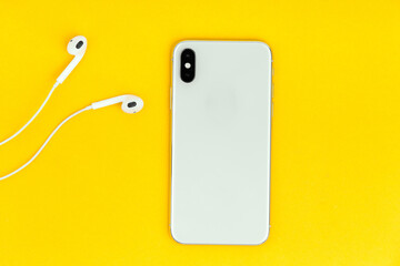 View from above at the phone and headphones on the yellow background.