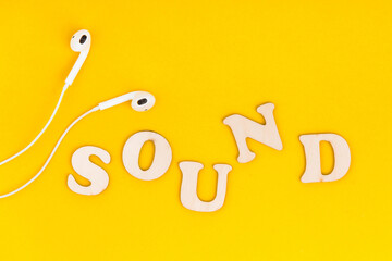 View from above at the headphones and word sound on the yellow background.