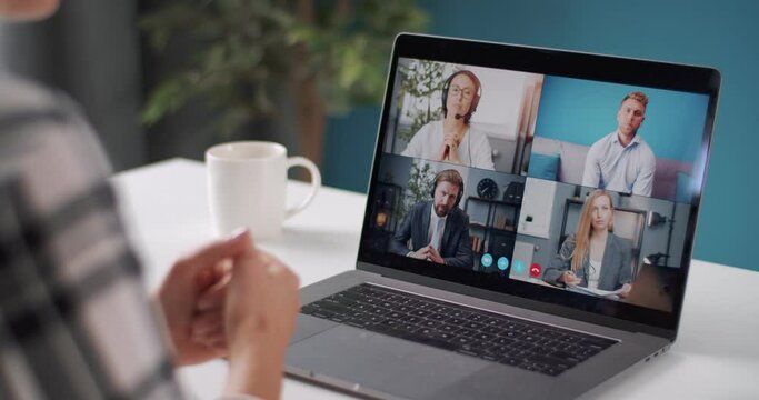 View from shoulder of business woman in domestic outfit using computer for video conference. Coworkers discussing working issues through online communication.