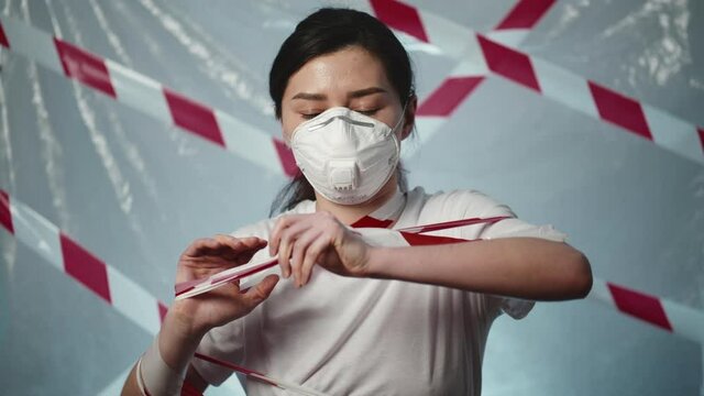 Portrait of an angry tired woman patient tear off a signal tape and a medical mask. Concept of end of the coronavirus epidemic, pandemic recovery, opening borders. The fight against covid-19