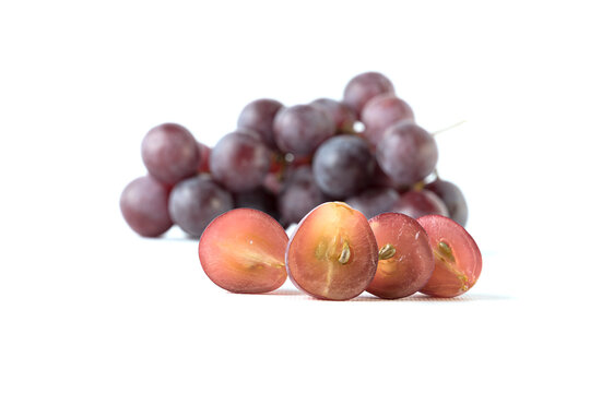 Image of grapes cut with a bunch of grapes out of focus, white background.