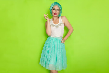 Portrait of a beautiful young woman with short blue hair in a studio on a green background