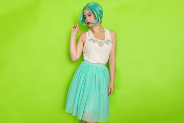 Portrait of a beautiful young woman with short blue hair in a studio on a green background