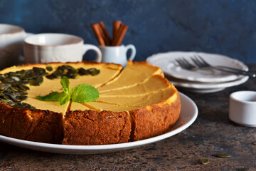 Homemade classic pumpkin cheesecake on a blue concrete background. Horizontal focus.
