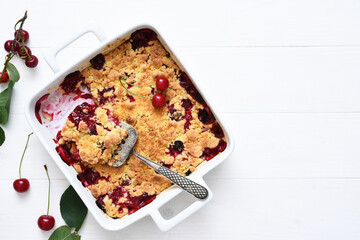 Homemade summer dessert with cherries. Crumble with cherries in a baking dish on a white background.