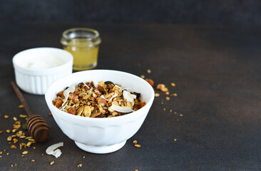Classic breakfast - granola with honey, coconut, yogurt and berries on a black background.