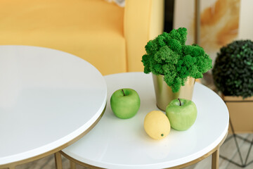 Still life, fruit apples and lemon, on a table in a modern interior, home plant in a pot.