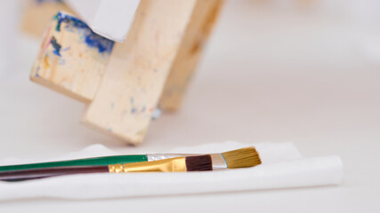 three brushes on a napkin lie on the table near the easel filmed close