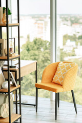 Home Office. By the panoramic window is a wooden table with a laptop, a yellow armchair, and a bookcase. Workplace at home.