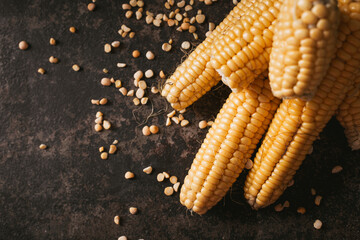 Ripe corn with pea seed on dark background.