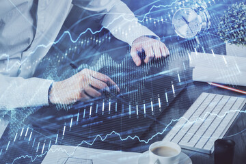 Double exposure of man's hands holding and using a phone and financial graph drawing. Analysis concept.