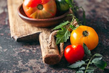 Fresh, ripe multi colored tomatoes on a dark background. Organic food.