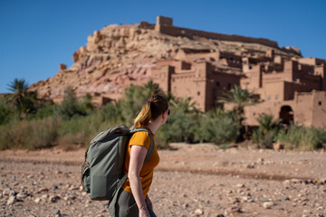 Female hiker with backpack looking at ksar while walking on land