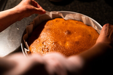 Freshly baked hot cake on top of the kitchen marble. Preparing a homemade cake at home in the kitchen with warm light.