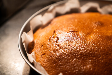 Close up view of a delicious homemade cake just out of the oven with warm kitchen light. Freshly baked hot cake on top of the kitchen marble.