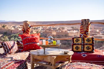 Abwaschbare Fototapete Marokko Wasserkocher mit Trinkgläsern im Tablett auf Holztisch im Dachrestaurant gegen klaren Himmel