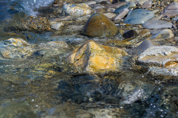 pebble stones on the sea beach, the rolling waves of the sea with foam