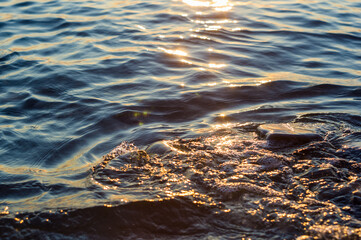 pebble stones on the sea beach, the rolling waves of the sea with foam