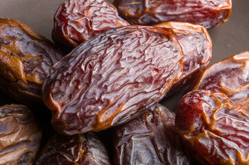 Big luxury dried date fruit in bowls on the dark surface, kurma ramadan kareem concept, close up.
