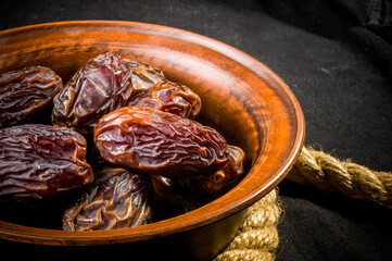 Big luxury dried date fruit in bowls on the dark surface, kurma ramadan kareem concept, close up.