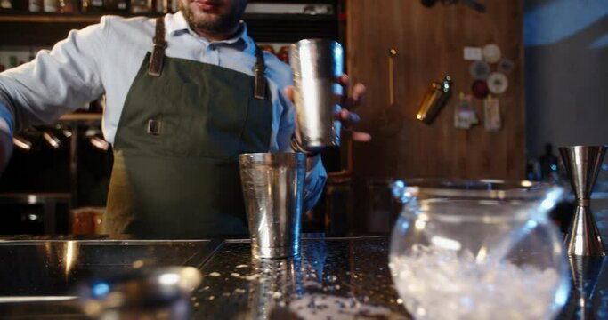 Authentic professional bartender flaring his shaker before making a cocktail. Experienced barman juggling with his equipment - food and drink 4k footage
