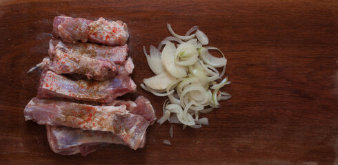 Pork ribs and onion in a wood table. Raw meat. Top view