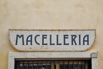 Close-up of a rusty metal shop sign with the Italian writing: 