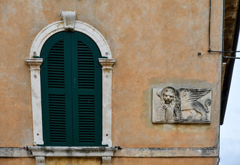 Obraz premium Exterior of an old house with an arched window and an ancient bas-relief that represents the winged Lion of Saint Mark, symbol of the city of Venice and formerly of the Venetian Republic, Italy