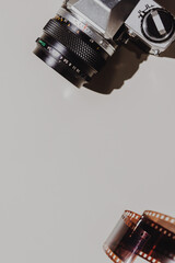 Geometric Flat lay set: vintage camera on light backgrounds with 35 mm filmstrip. Top view.
