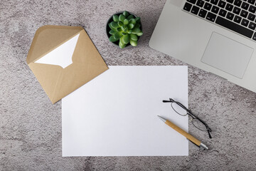 Workplace with blank paper, wooden pen and laptop on stone background. Home or in the office