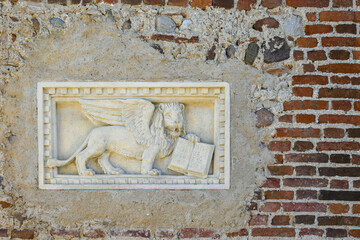 Detail of a stone bas-relief with the Lion of St Mark, a winged lion holding a bible, symbol of the city of Venice, Italy