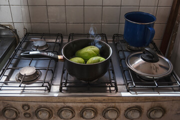 A saucepan in an old stove cooking some chayotes green vegetables