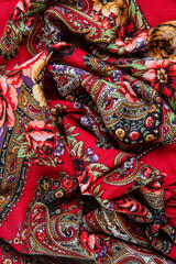 vertical view closeup on crumpled red cotton scarf with bright paisley floral ornament