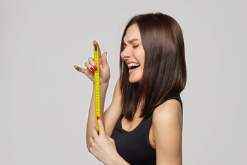 beautiful girl holds a measuring tape in her hands. the concept of imagination about the size of the penis...
