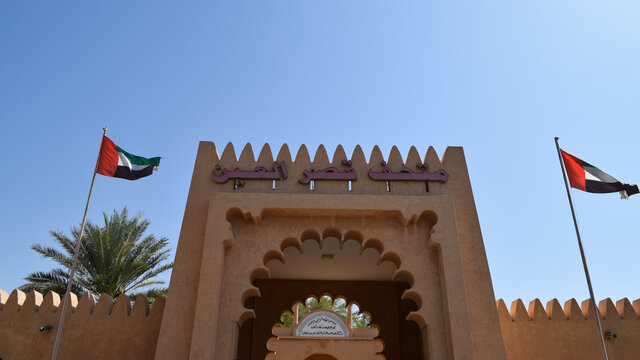 A multifoil arch and two flags in the entrance of a museum in the city of Al Ain, United Arab Emirates, in a sunny day.