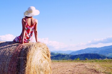 young woman sitting on hay bale