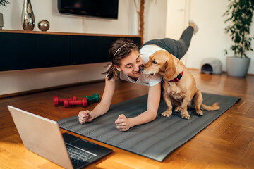 girl watching exercise tutorials online with her dog