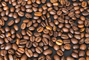 Coffee beans on a black table fill the whole space, wallpaper or background