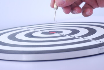 Fototapeta na wymiar Hand gold red dart arrow hitting in the target center of dartboard