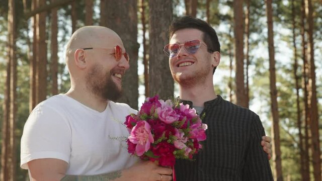 Portrait of queer couple happy together. Gay wedding concept. Two men with flower bouquet and ring on finger smile and hug. Relationship Goals. LGBTQI, Pride Event, LGBT Pride Month, Gay Pride Symbol