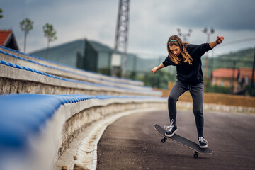 Teenage girl performing skateboard tricks on the sports field.