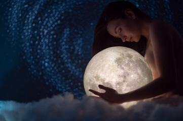 Naked girl with the moon in her hands on a background of stars, femininity and beauty female,...