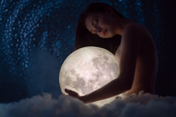Female tenderness, a beautiful girl holds the moon against the background of stars and sky, zodiac...