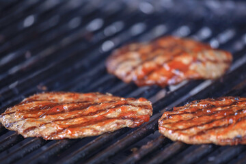 three hamburger patties on a grill